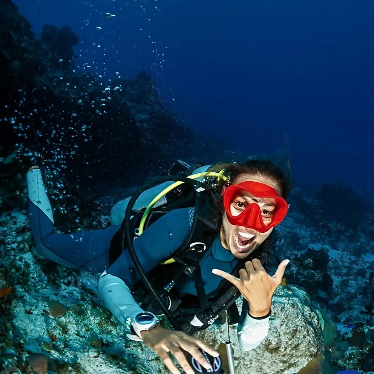 A vibrant red diving mask with a clear lens, worn by an underwater diver.